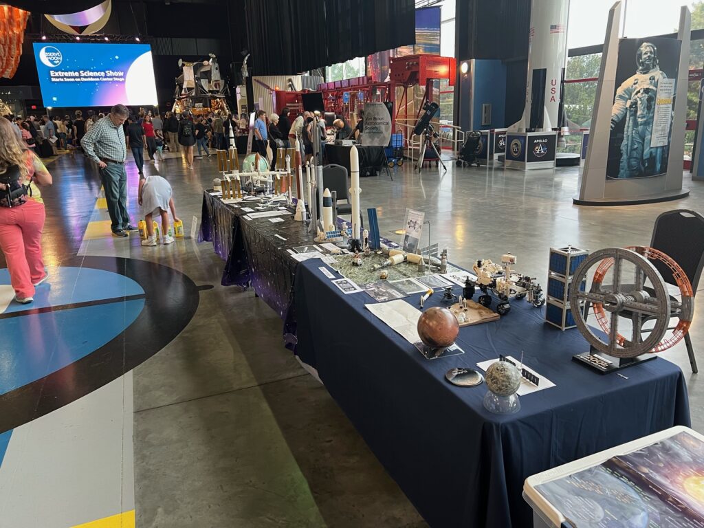 Actual size cubesat next to not actual size 2001: A Space Odyssey Space Station V (~1:2000 scale) at table end. And Apollo Lunar module at the other end of the museum.